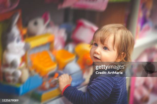 happy little boy choosing toy in a store - loja de brinquedos imagens e fotografias de stock