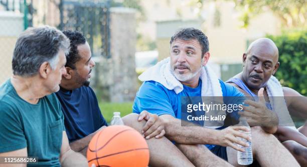 group of men hanging out on basketball court, talking - mature men playing basketball stock pictures, royalty-free photos & images