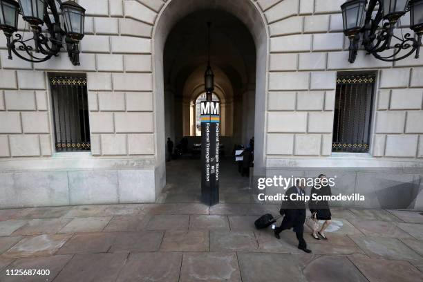 Federal employees step out of the Federal Triangle Metro station at the Wilson Plaza and Ronald Reagan Building where The U.S. Agency for...