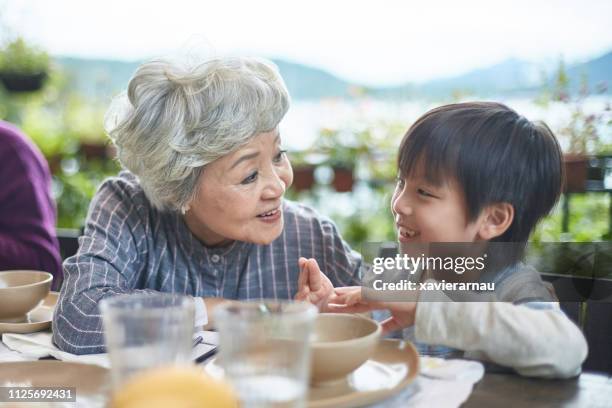 happy grandmother listening to boy during lunch - child listening differential focus stock pictures, royalty-free photos & images