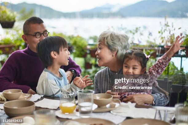 happy grandparents playing with children at table - hong kong grandmother stock pictures, royalty-free photos & images