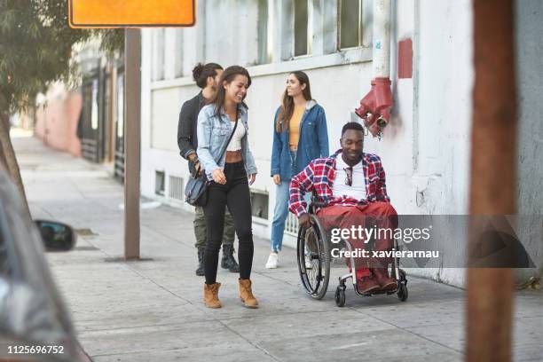 friends walking with disabled man on sidewalk - pedestrian path stock pictures, royalty-free photos & images