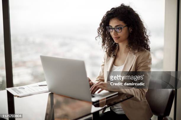 businesswoman working on laptop at a cafe - businesswoman hotel stock pictures, royalty-free photos & images