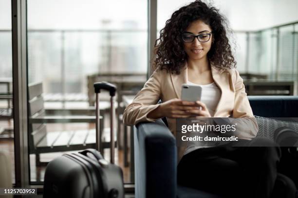 young businesswoman using mobile phone at a cafe - airport waiting lounge imagens e fotografias de stock