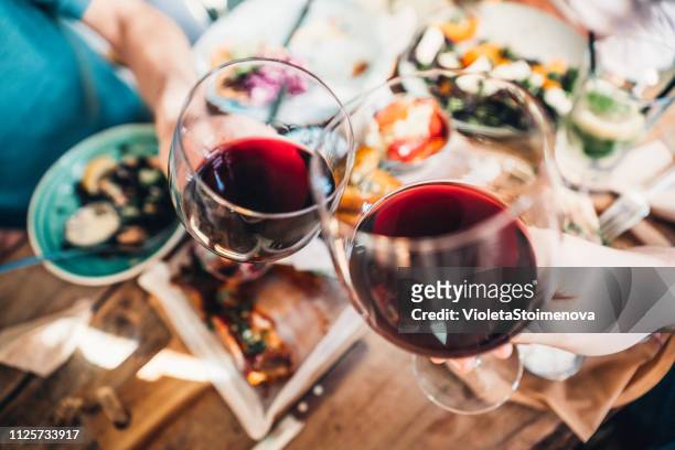food and wine brings people together - friends toasting above table stock pictures, royalty-free photos & images