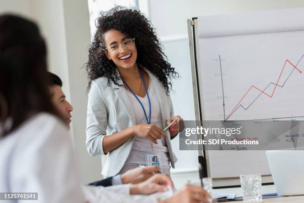 young businesswoman gives presentation to colleagues - business sale stock pictures, royalty-free photos & images