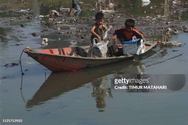 Two Indonesian boys salvage items from the polluted Citarum river in Bojongsoang, Bandung regency on February 19, 2019. - The World Bank declared the...