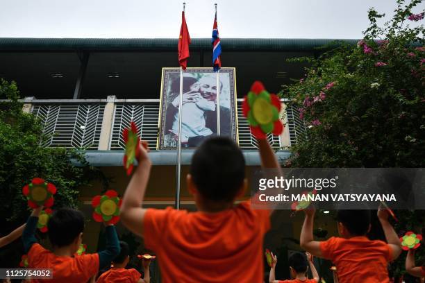 North Korean and Vietnamese flags are seen in front of a portrait of the late Vietnamese leader, Ho Chi Minh as school children perform morning...