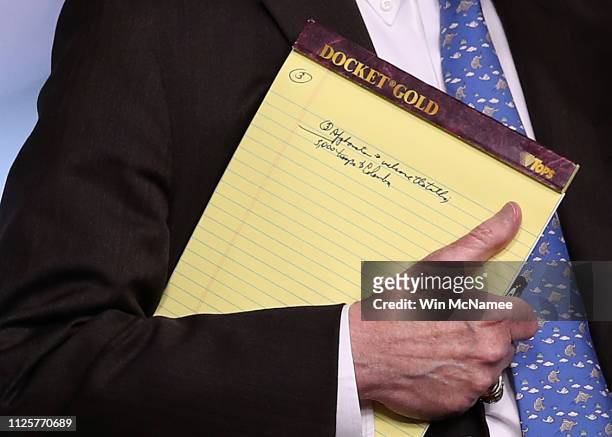 With handwritten notes on a legal pad, National Security Advisor John Bolton listens to questions from reporters during a press briefing at the White...