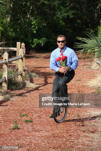 man on unicycle delivering flowers - fault sports stock pictures, royalty-free photos & images