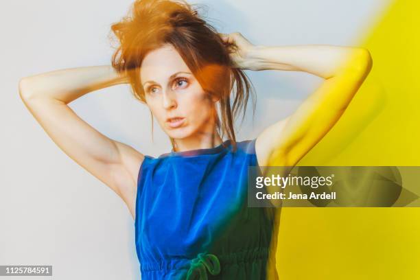waist up creative portrait of woman fixing hair, woman putting up hair, long hair, messy hair - yellow retro dress stock pictures, royalty-free photos & images