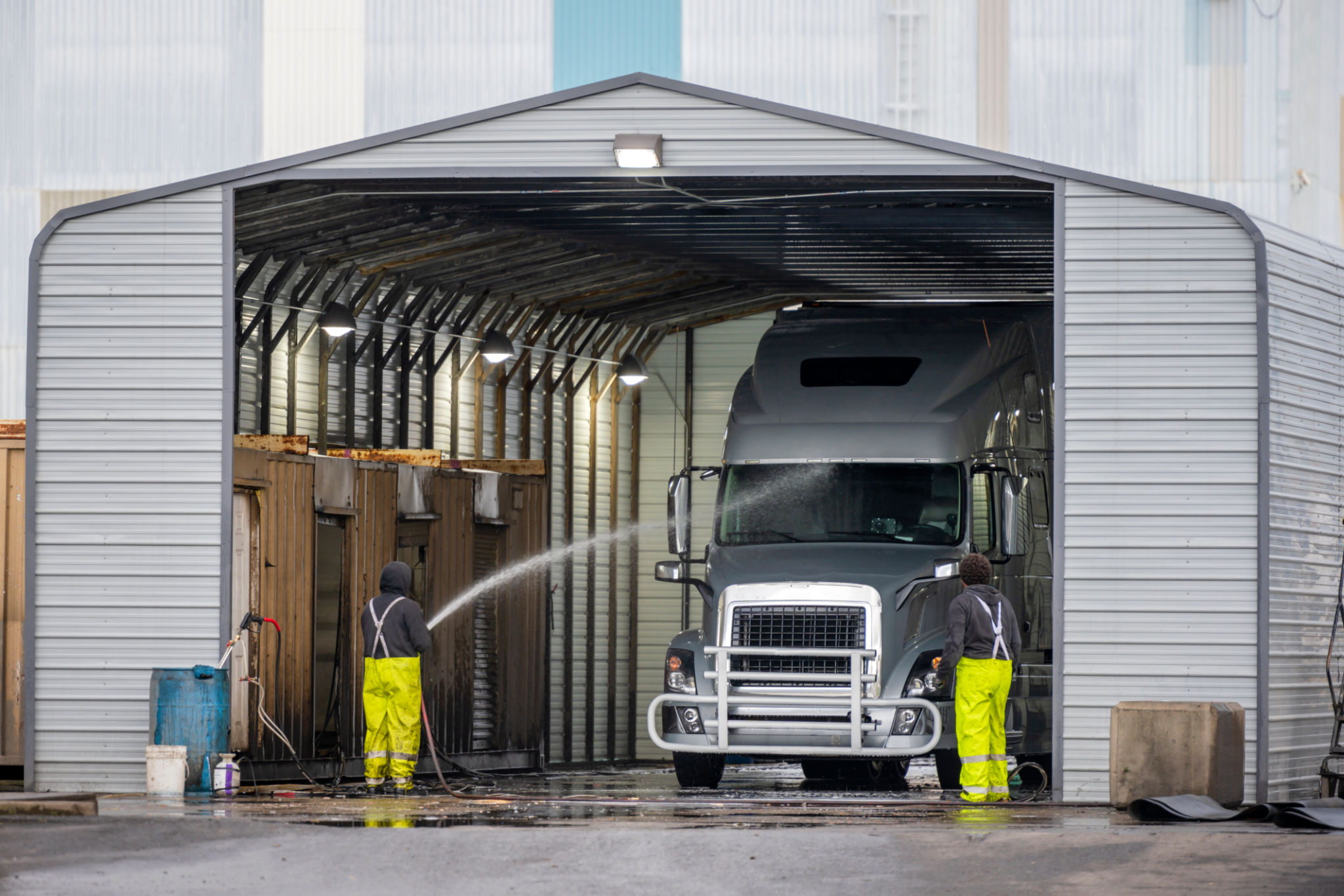 Big rig semi truck washes in covered car wash station with manual washing Big rig semi truck washes in covered car wash station with manual washing