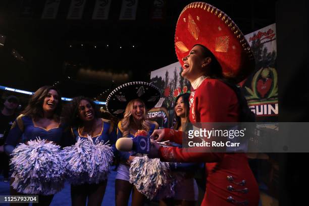 Reporter from Televisa gives food to a Los Angeles Rams cheerleader during Super Bowl LIII Opening Night at State Farm Arena on January 28, 2019 in...