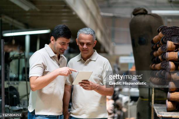 supervisor and employee looking at a tablet while pointing at something smiling - shoe factory stock pictures, royalty-free photos & images