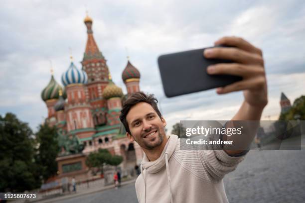 hombre tomando un selfie en moscú en la plaza roja frente a la catedral de san basilio - plaza roja fotografías e imágenes de stock