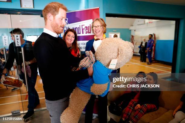 Britain's Prince Harry, Duke of Sussex is given the gift of a large teddy bear during his visit to a Fit and Fed half-term initiative in Streatham,...