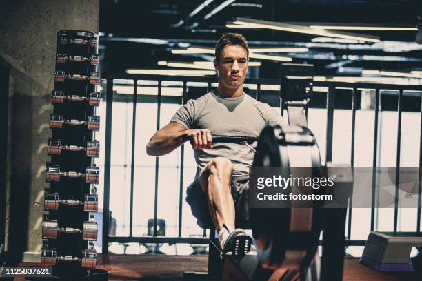 ジムでクロストレーニングワークアウトをしている男 - フィットネスマシン ストックフォトと画像
