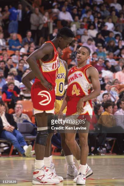 Spud Webb of the Atlanta Hawks listens to teammate Dominique Wilkins during a NBA game against the Los Angeles Lakers at the Great Western Forum in...