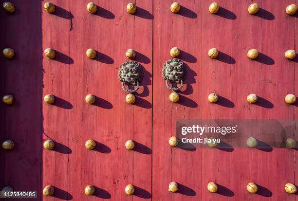 pair of gold colored lion head shaped handles on red doors - doorknob stock pictures, royalty-free photos & images