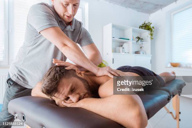 rückseite des jungen mannes massieren massage-therapeut - masseur stock-fotos und bilder