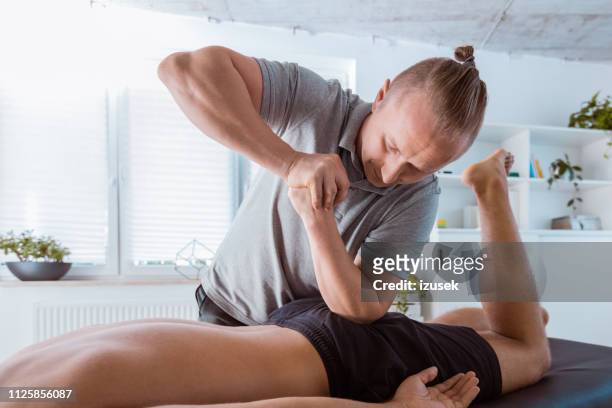 physiotherapist massaging young man - beautiful bums imagens e fotografias de stock