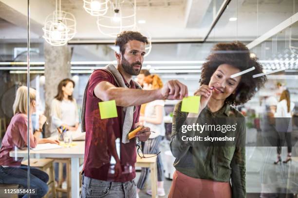 young creative people making plans on a glass wall at casual office. - pricing strategy stock pictures, royalty-free photos & images