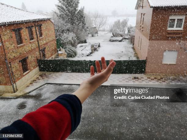 child reaching out to touch snow from window - catching snow stock pictures, royalty-free photos & images