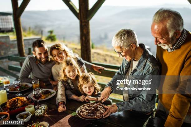 happy mature woman cutting sweet pie for her family on a terrace. - man eating pie stock pictures, royalty-free photos & images
