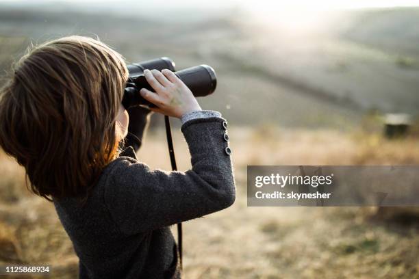 niño pequeño mirando a través de binoculares en la naturaleza. - mirar a través fotografías e imágenes de stock