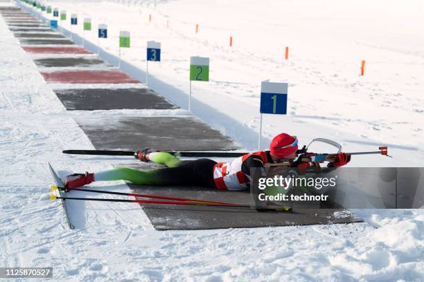 side view of young male biathlon competitor practicing target shooting, lying position - biathlon ski stock pictures, royalty-free photos & images