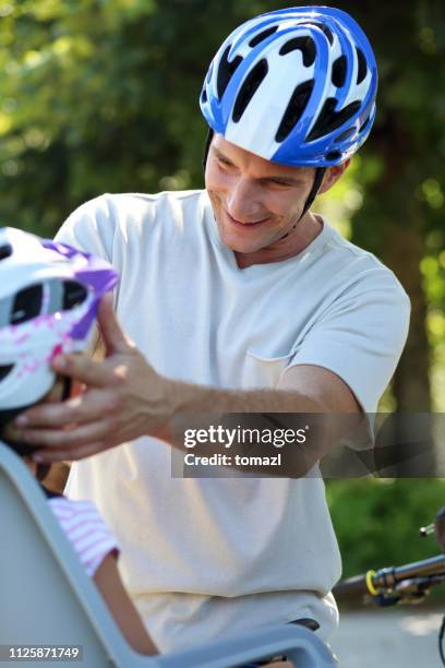 father adjusting his son's cycling helmet - father helping son wearing helmet stock pictures, royalty-free photos & images