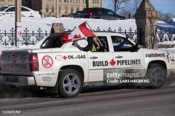 Woman waves a Canadian flag during the Convoy for Canada protest on Parliament Hill in Ottawa, Ontario, on February 19, 2019. - A convoy of big...