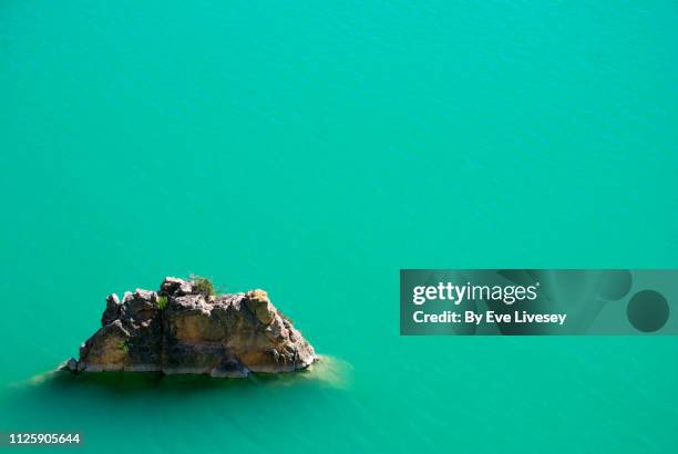 rock in a turquoise lake - smaragdgroen stockfoto's en -beelden