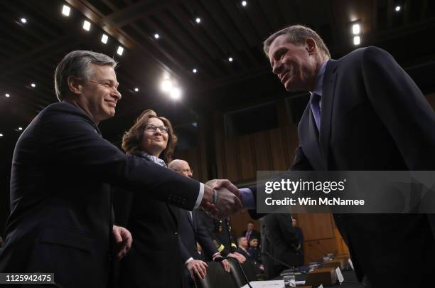 Senate Intelligence Committee Ranking Member Sen. Mark Warner shakes hands with Christopher Wray , director of the Federal Bureau of Investigation as...