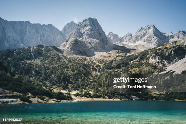 crystal blue water at lake seebensee with a view to the mountain vorderer drachenkopf - zugspitze stock pictures, royalty-free photos & images