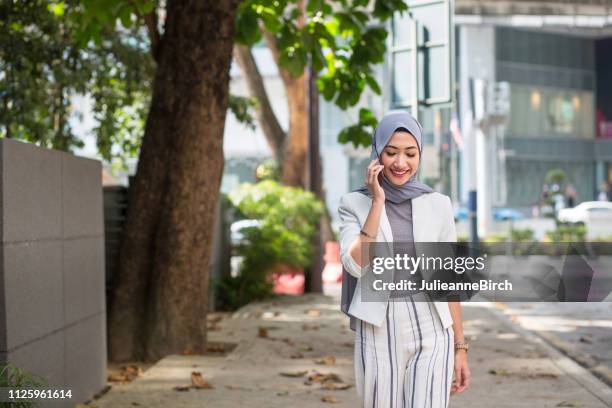 femme d’affaires à l’aide de téléphone portable sur le trottoir - voile religieux photos et images de collection
