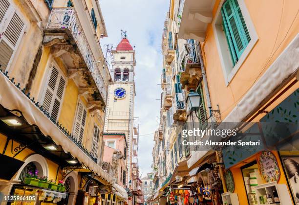 narrow shopping street and st. spyridon church bell tower in corfu town, corfu, greece - corfu town stock pictures, royalty-free photos & images
