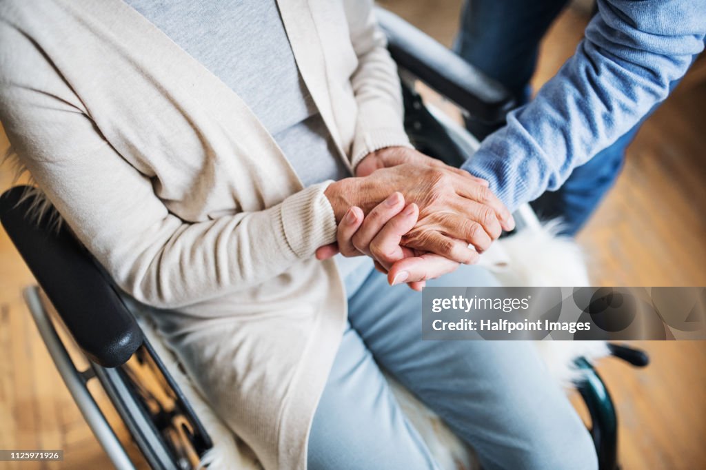 A midsection of senior couple at home, a husband looking after his disabled wife.