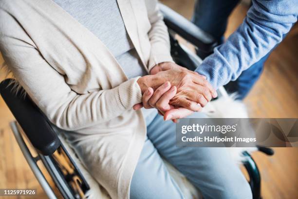 a midsection of senior couple at home, a husband looking after his disabled wife. - weakness fotografías e imágenes de stock