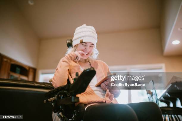 cheerful woman in wheelchair on smartphone at home - cadeira de rodas imagens e fotografias de stock