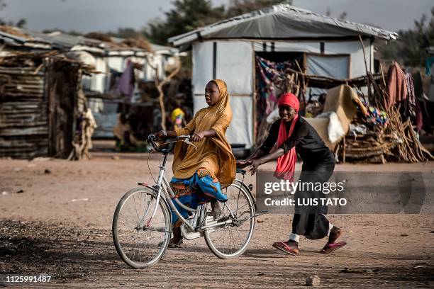 Two girls play while riding a bicycle at Malkohi refugee camp in Jimeta, Adamawa State, Nigeria on February 19 four days ahead of the country's...