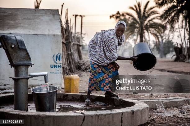 Woman pours water from a well at Malkohi refugee camp in Jimeta, Adamawa State, Nigeria early on February 19 four days ahead of the country's General...