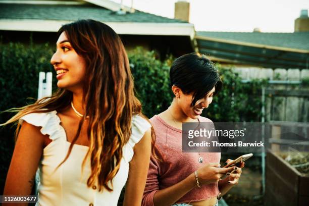 Laughing adult sisters hanging out in backyard during party on summer evening