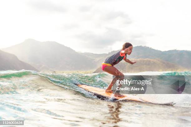 cute little girl surfing - indonesia surfing imagens e fotografias de stock