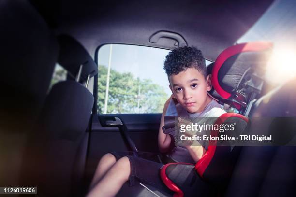 child seated in the safety seat in the back seat of the car putting on his seat belt - rücksitzbank im auto stock-fotos und bilder