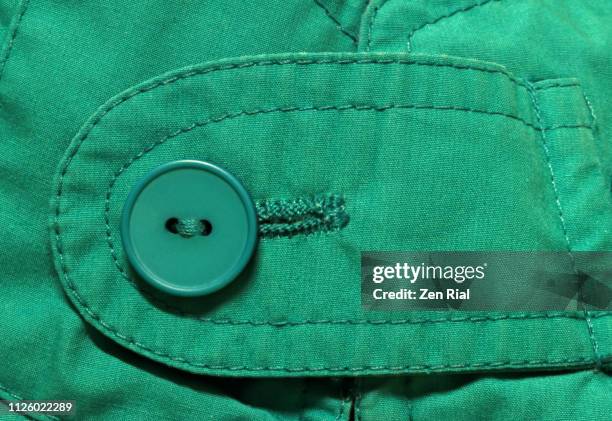 extreme close up of a single green button on green fabric - winter coat stock pictures, royalty-free photos & images