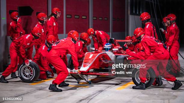 boxenstopp-team arbeitet an einem roten formel-rennwagen - boxenstopp stock-fotos und bilder