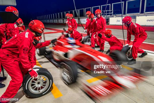 coche de carreras fórmula roja dejando el pit stop - carrera de coches fotografías e imágenes de stock