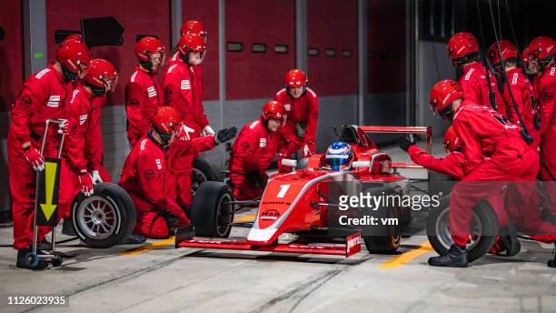 pit crew preparing to change tires on formula car - pit stop stock pictures, royalty-free photos & images