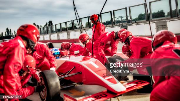 mechanics changing tires on a formula during a pit stop - pit stop stock pictures, royalty-free photos & images